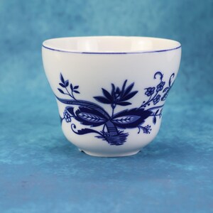 May include: A white ceramic mug with a black handle and the text "But First, Coffee" in a black, handwritten-style font. The mug is on a white surface.