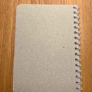 Pu&ograve; includere: Un quaderno marrone con una rilegatura a spirale. Il quaderno ha una copertina in carta testurizzata.