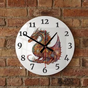 Könnte beinhalten: Runde weiße Wanduhr mit einer farbenfrohen Drachenillustration. Der Drache ist in Rot-, Orange-, Gelb- und Blautönen dargestellt. Schwarze Zeiger zeigen die Uhrzeit an. Die Uhr ist an einer Backsteinmauer befestigt. Durchmesser ca. 30 cm.