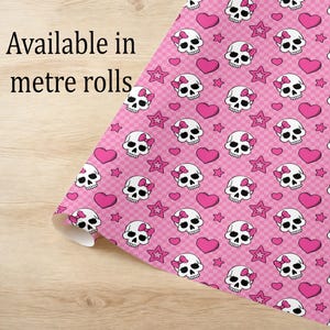 May include: Pink patterned fabric with white skulls wearing pink bows, pink hearts, and pink stars. The fabric is available in meter rolls. The background is a light pink checkered pattern.