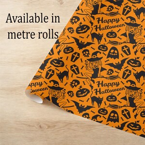 May include: Orange Halloween-themed wrapping paper with a repeating pattern of black witch illustrations, cats, bats, pumpkins, and the text "Happy Halloween." The text "Available in metre rolls" is also visible.