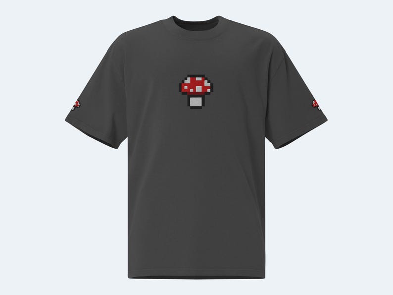 May include: A dark gray t-shirt with a pixelated red and white mushroom graphic on the front.