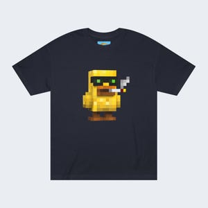 May include: Navy blue t-shirt featuring a pixelated yellow duck wearing sunglasses and smoking a cigarette. The duck has brown feet and a large orange beak. The shirt has a small, colorful logo on the upper back.