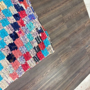 May include: A colorful, handwoven rug with a variety of blues, reds, and pinks. The rug is made of recycled materials and has a unique, textured look.