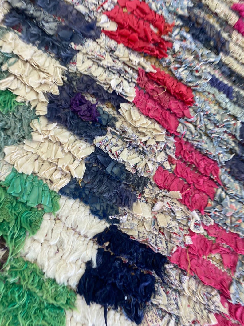 May include: A colorful rag rug with a variety of colors including green, white, blue, pink, and red. The rug is made of recycled fabric and has a unique, handmade look.