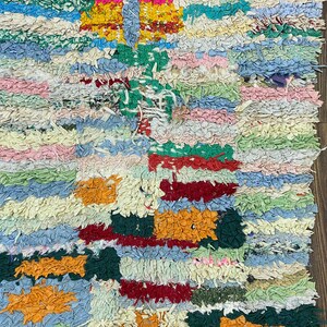 Puede incluir: Una alfombra colorida y texturizada con un dise&ntilde;o de patchwork. La alfombra presenta una variedad de colores, incluyendo azul, verde, rosa, amarillo y naranja. La alfombra est&aacute; hecha de tiras de tela y tiene un aspecto hecho a mano.