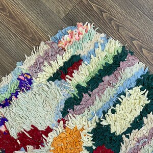 Puede incluir: Una colorida alfombra de trapo con dise&ntilde;o de patchwork. La alfombra presenta una variedad de colores, incluyendo crema, rojo, verde, azul y naranja. La alfombra est&aacute; hecha de tiras de tela y tiene una apariencia texturizada.