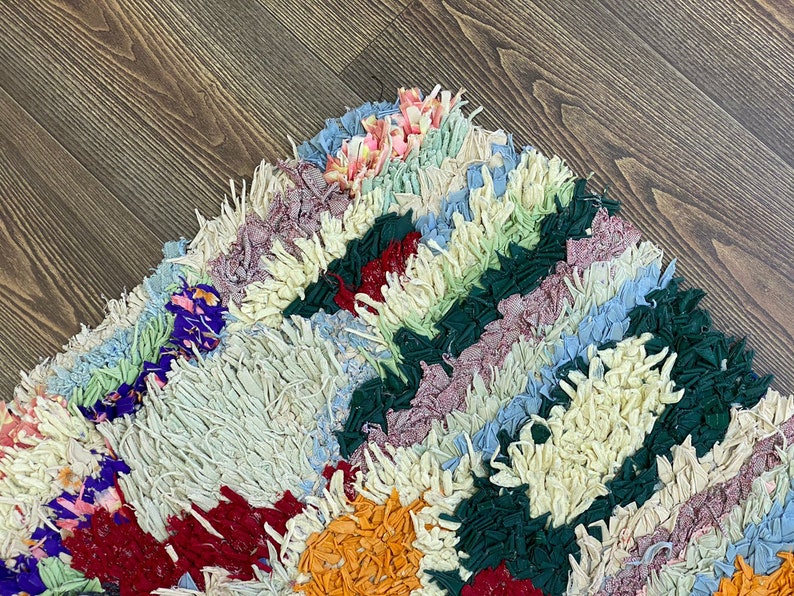 Puede incluir: Una colorida alfombra de trapo con dise&ntilde;o de patchwork. La alfombra presenta una variedad de colores, incluyendo crema, rojo, verde, azul y naranja. La alfombra est&aacute; hecha de tiras de tela y tiene una apariencia texturizada.