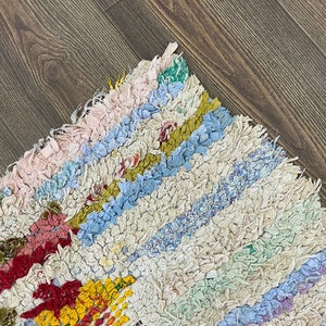 Puede incluir: Una colorida alfombra de trapo hecha a mano con un patr&oacute;n de rayas. La alfombra presenta una variedad de colores, incluyendo rosa, azul, amarillo y rojo. La alfombra est&aacute; hecha de tiras de tela y tiene una apariencia texturizada. Adecuada para la decoraci&oacute;n del hogar.