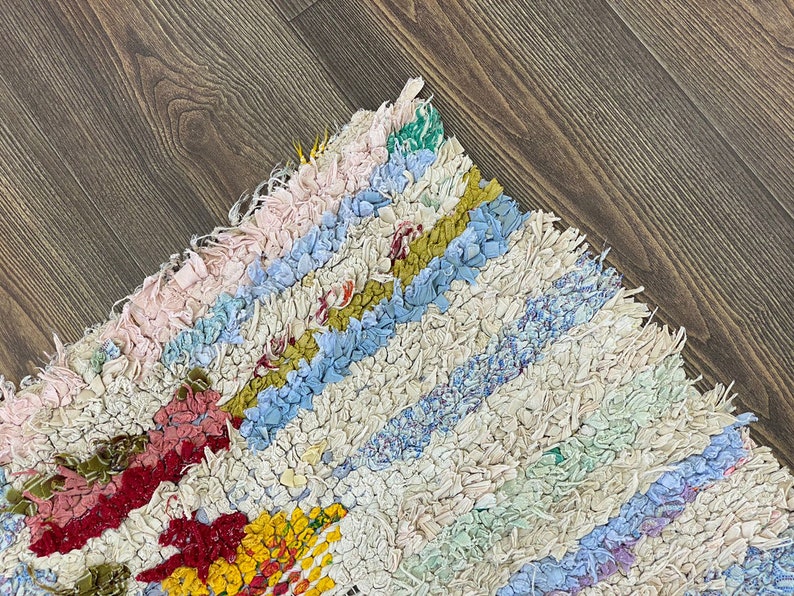 Puede incluir: Una colorida alfombra de trapo hecha a mano con un patr&oacute;n de rayas. La alfombra presenta una variedad de colores, incluyendo rosa, azul, amarillo y rojo. La alfombra est&aacute; hecha de tiras de tela y tiene una apariencia texturizada. Adecuada para la decoraci&oacute;n del hogar.