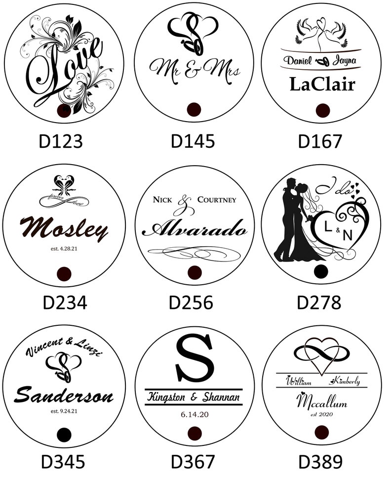 May include: Nine round, white, wooden signs with black text and designs. The signs feature various wedding-themed designs, including hearts, doves, and wedding rings. The text on the signs includes names, dates, and phrases like "Mr. & Mrs." and "I do".