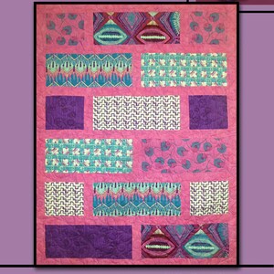 May include: A quilt pattern called "Ebb Tide" by Villa Rosa Designs. The quilt features a pink background with a variety of geometric and floral patterns in shades of purple, blue, and green.
