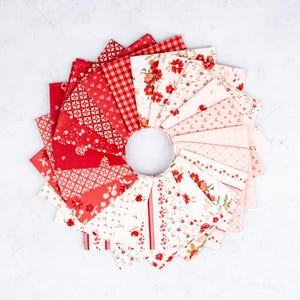 May include: A circular arrangement of folded fabric squares featuring a gradient of red and white patterns. The collection includes solid red, gingham, floral prints, and geometric designs, transitioning from deep red to light pink and white.