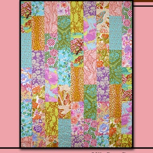 May include: A colorful patchwork quilt with the text "SPICE DROP" and "Villa Rosa Designs". The quilt features a variety of floral, animal print, and patterned fabrics in shades of pink, green, purple, and gold. A pink rose is in the upper right corner.