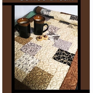 May include: A brown and beige quilted table runner with a coffee cup and saucer on top. The table runner has a variety of patterns, including swirls, circles, and leaves. The text "Coffee Break" is at the top of the image. The text "Tricia Lynn Maloney Orphan Quilt Designs For Villa Rosa Designs" is at the bottom of the image.