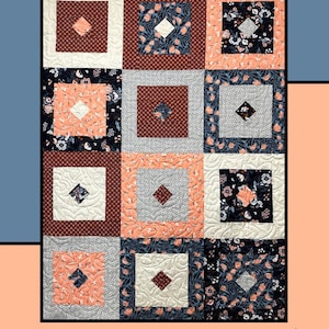 May include: A quilt pattern called "Sushi" by Heidi Cook for Villa Rosa Designs. The quilt is made up of nine squares, each with a different fabric pattern. The fabrics are in shades of peach, brown, white, and blue.