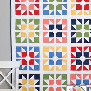 May include: A colorful quilt with a repeating pattern of split star blocks in red, blue, green, and yellow. The quilt is hanging on a wall next to a white chair. The text "Split Stars" is at the top.