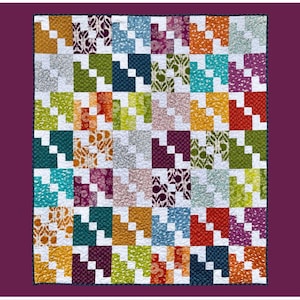May include: A colorful patchwork quilt with the word "Markesan" in a script font at the top. The quilt features a repeating pattern of squares in various colors, including orange, green, blue, and purple. The bottom of the image includes text that reads "Rachelle for Handmade Villa Rosa Designs."