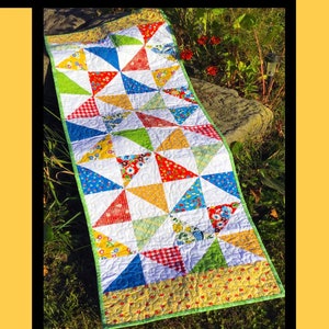 May include: A colorful quilt pattern called "Pinwheel Picnic" by Tricia Lynn Maloney for Villa Rosa Designs. The quilt is made with a variety of fabrics in red, blue, yellow, green, and white.