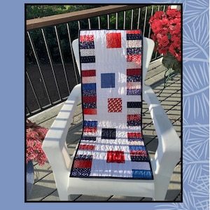 May include: A red, white, and blue quilted table runner with a geometric pattern. The runner is on a white chair on a wooden deck. The text "Sew Charmed" is at the top of the image. The text "Sugar Pine Quilt Designs for Villa Rosa Designs" is at the bottom of the image.