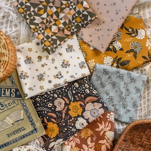 Puede incluir: Una colección de muestras de tela con varios patrones florales y geométricos en tonos verde oliva, amarillo mostaza y marrón. Algunas telas presentan pequeñas estampas florales, mientras que otras tienen flores más grandes. También se ve un libro antiguo y un ribete de encaje.