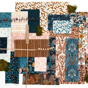Puede incluir: Una colección de muestras de tela rectangulares con diversos patrones, incluyendo diseños florales, botánicos y geométricos en tonos azul verdoso, azul marino, óxido, crema y rosa, acentuados con pequeños trozos de musgo verde y palos de madera.