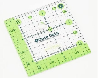 Könnte beinhalten: Ein quadratischer, transparenter Lineal aus Kunststoff mit grünen Markierungen. Das Lineal ist quadratisch und hat ein Raster mit Zollmaßen. Das Lineal ist mit "Cute Cuts" und "Ruler Blake" beschriftet.