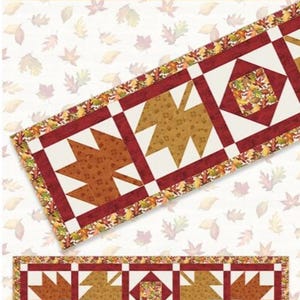 May include: A fall-themed table runner with a leaf pattern. The runner is 20 inches by 76 inches and features a repeating design of stylized leaves in shades of brown and gold, framed by a burgundy border. The text "Fall Hues Table Runner" is visible.
