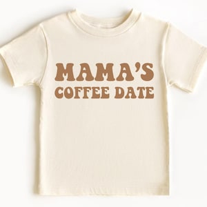 May include: A white short-sleeved t-shirt with the text "MAMA'S COFFEE DATE" in brown letters.