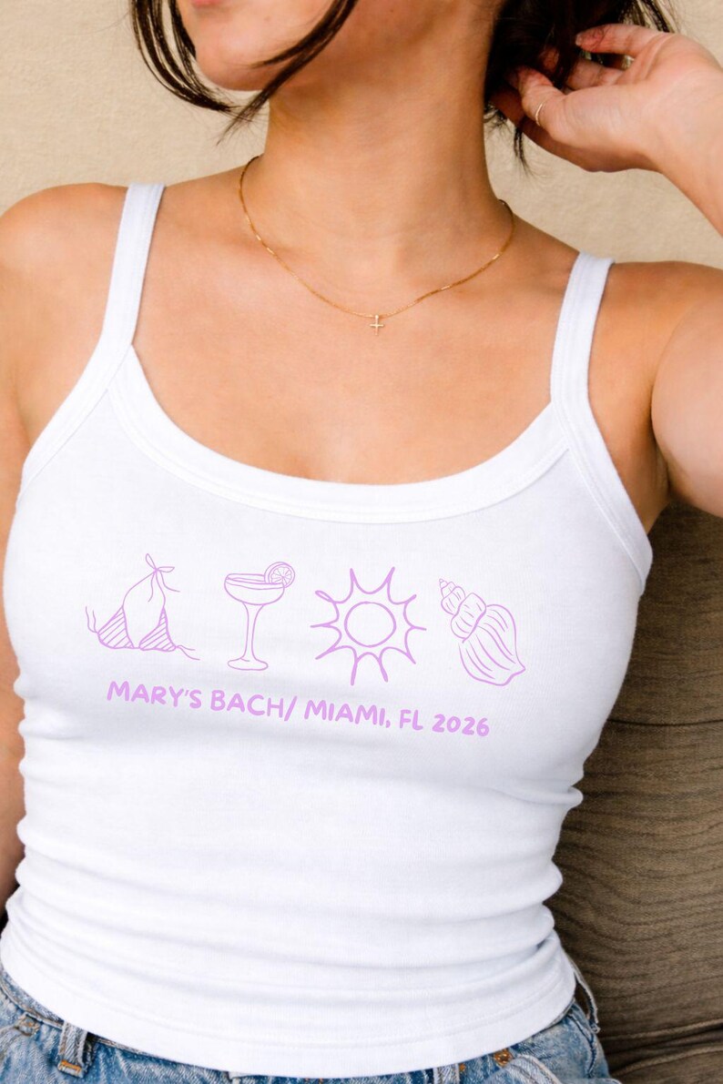 May include: White tank top with a scoop neck and thin straps. The shirt features a purple graphic of a bikini, cocktail, sun, and seashell. Text at the bottom reads "MARY'S BACH/ MIAMI, FL 2026".