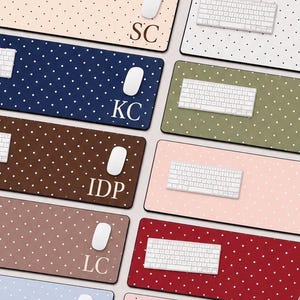 May include: A collection of rectangular desk mats in various colours including beige, navy blue, brown, light brown, light blue, white, olive green, pink, and red, all featuring a white polka dot pattern and some personalised with initials.
