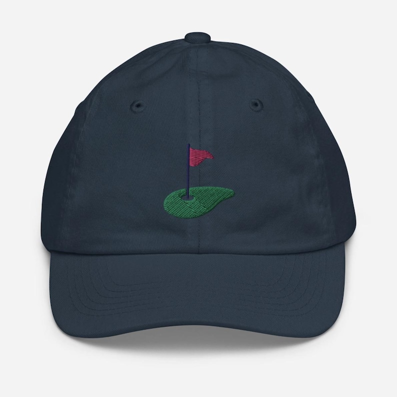 May include: A navy blue baseball cap with an embroidered green golf course and red flag.
