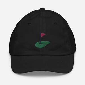 May include: Black baseball cap with an embroidered green golf course and red flag.