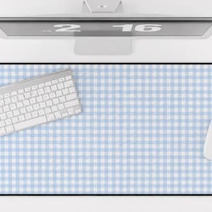 May include: A rectangular desk mat featuring a light blue and white gingham check pattern with a black border. The mat is positioned under a white computer keyboard and a white computer mouse, with a computer monitor visible at the top edge.