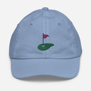 May include: A light blue baseball cap with an embroidered green golf green and a red flag.