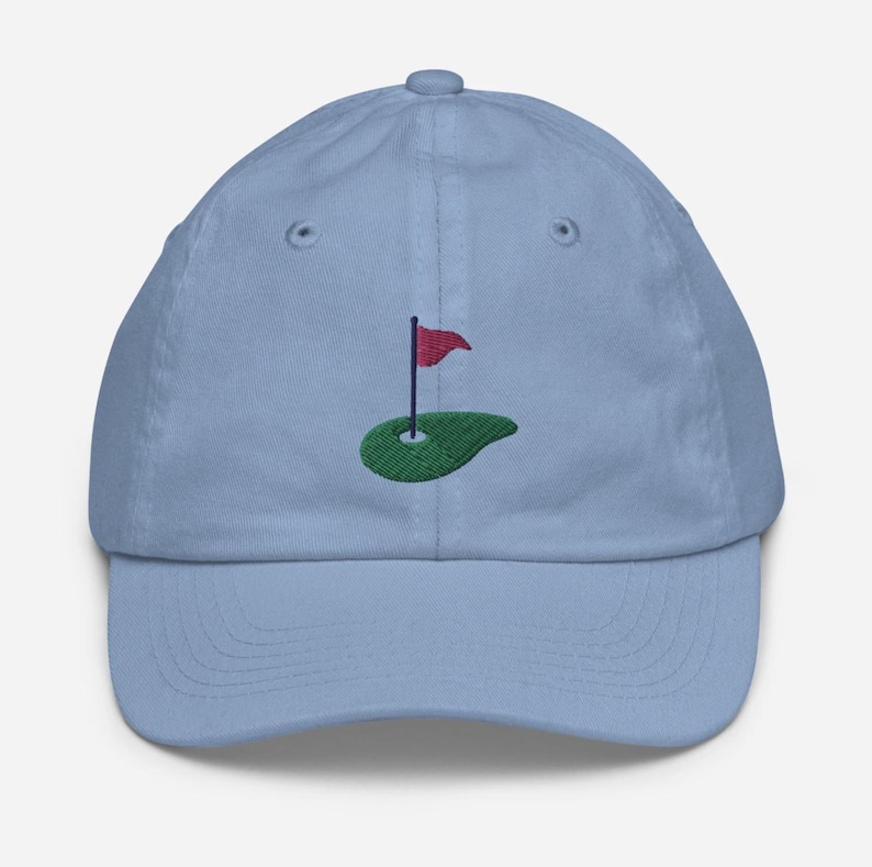 May include: A light blue baseball cap with an embroidered green golf green and a red flag.