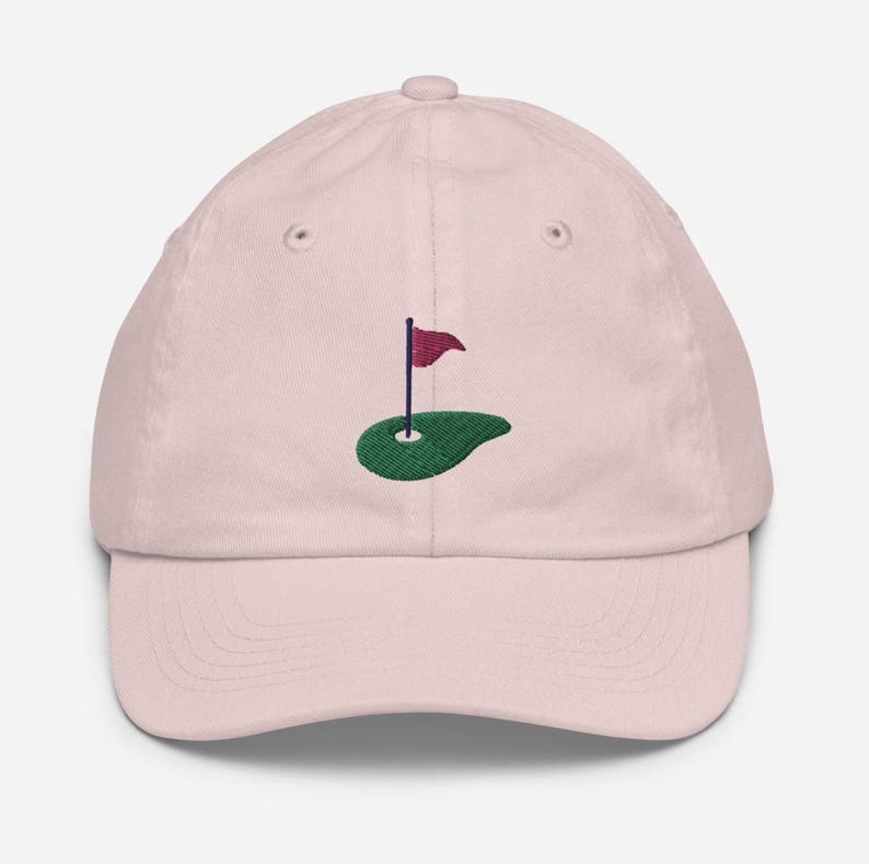 May include: A pink baseball cap with an embroidered green golf course and a red flag.