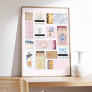 May include: A framed print of a collection of matchboxes with various designs, including a swan, a seashell, a floral pattern, a blue and white vase, and a bottle of champagne. The matchboxes are arranged in a grid pattern on a pink and white striped background.
