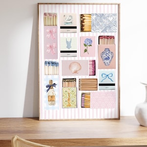 May include: A framed print of a collection of matchboxes with various designs, including a swan, a seashell, a floral pattern, a vase, a bow, a dress, and a bottle of perfume. The matchboxes are arranged in a grid pattern on a pink and white striped background.