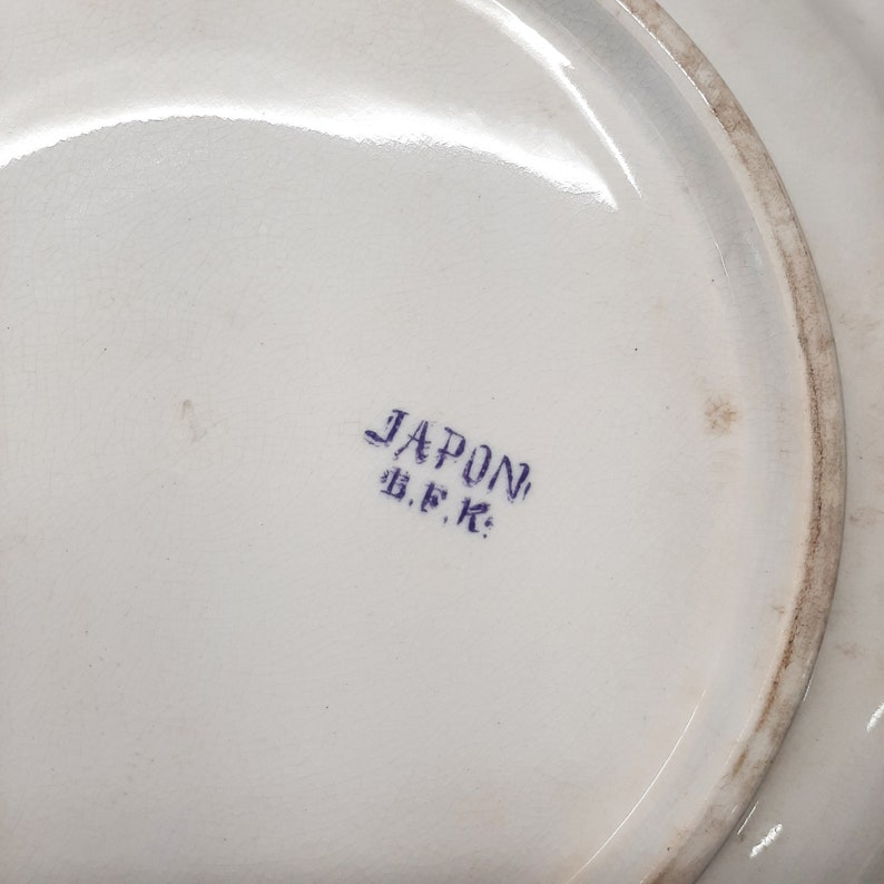 Puede incluir: Un plato de cer&aacute;mica blanco con un sello azul que dice "JAPON B.F.K."