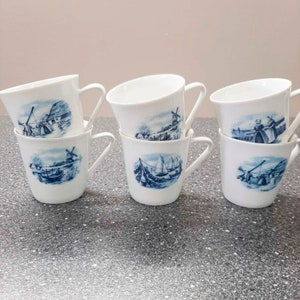 May include: Set of six white ceramic coffee mugs with blue and white Dutch windmill and boat designs.