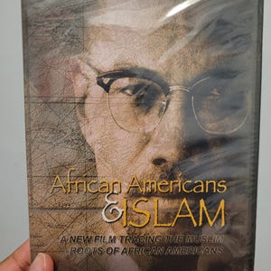 May include: A DVD case with a portrait of a man in glasses. The title "African Americans & Islam" is in gold and white. The subtitle reads "A NEW FILM TRACING THE MUSLIM ROOTS OF AFRICAN AMERICANS". The case is sealed in clear plastic.