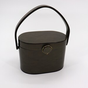 May include: A dark brown oval-shaped handbag with a top handle. The bag has a gold-colored clasp.