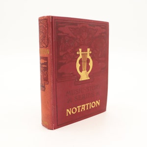 May include: A red book with gold lettering titled "Music Story Series: Notation". The cover features a gold lyre with wings on either side.