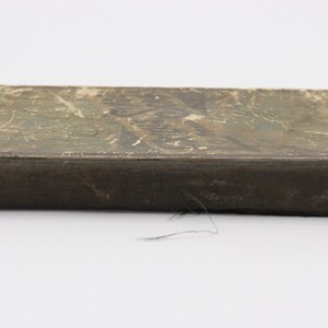 May include: A vintage, brown, rectangular box with a worn, green and white paper cover. The box has a faded, printed design on the top.