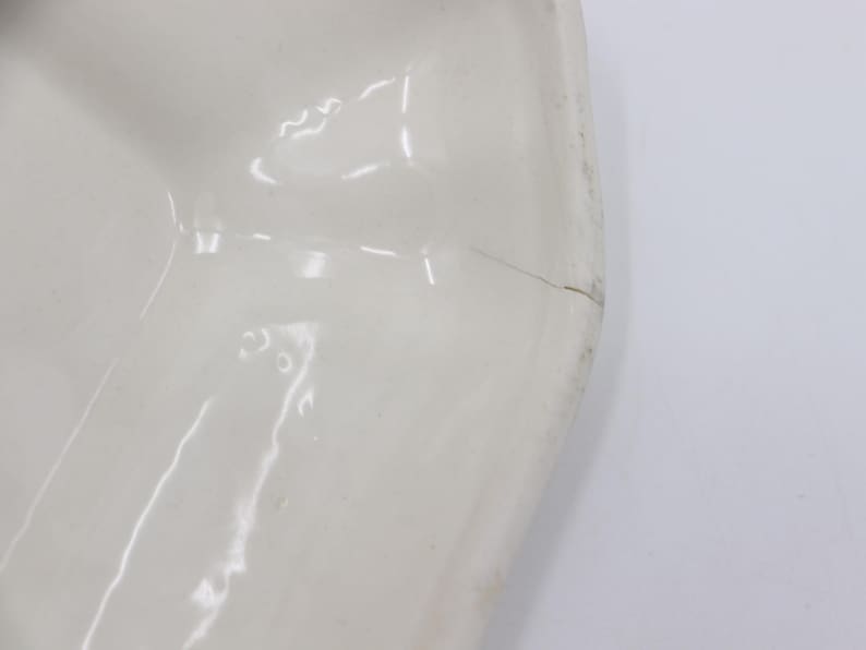 May include: White ceramic bowl with a scalloped edge. The bowl has a small crack on the side.