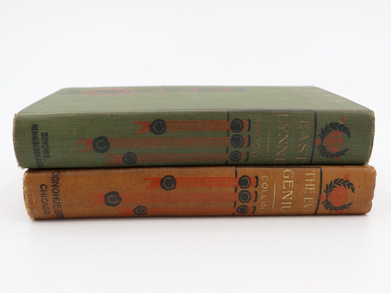 May include: Two vintage hardcover books stacked on top of each other. The top book is green with gold lettering that reads "The Evil Genius" by "East Lynne" and "Collins Wood". The bottom book is brown with gold lettering that reads "Donohue Bros. Chicago".