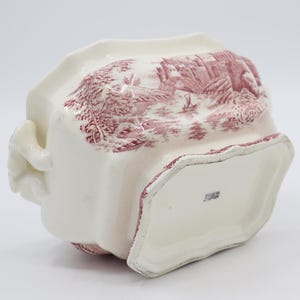 May include: White ceramic serving dish with a pink floral pattern and a scalloped edge. The dish has two handles and a raised base. The bottom of the dish has a stamp that reads "England".