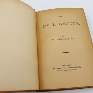 May include: The cover of a vintage book titled "The Evil Genius" by Wilkie Collins. The book was published by Donohue Brothers in Chicago.