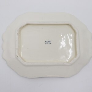 May include: White ceramic butter dish with a scalloped edge. The bottom of the dish has a blue stamp that reads "2418".
